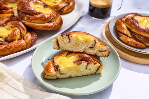 A sunshine bun sliced in half on a plate and others arranged in the background. - select to zoom
